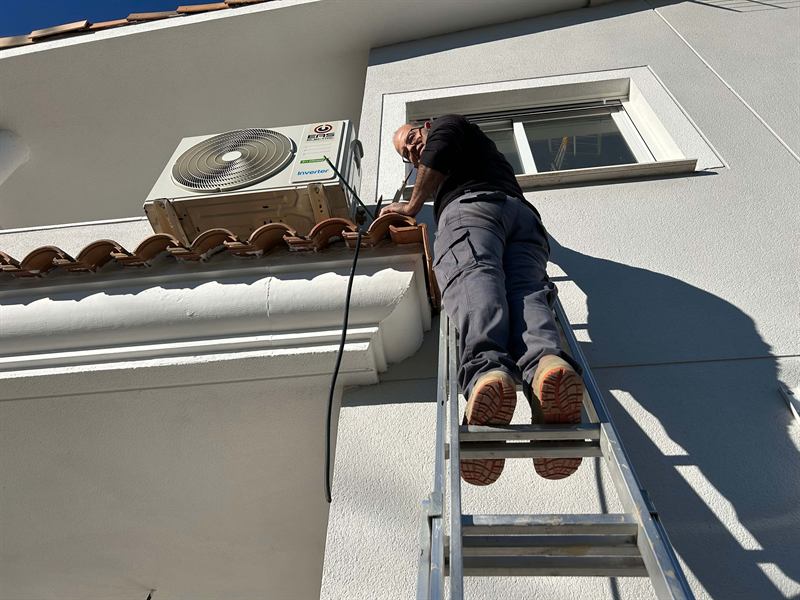 Técnico reparando unidad exterior de aire acondicionado